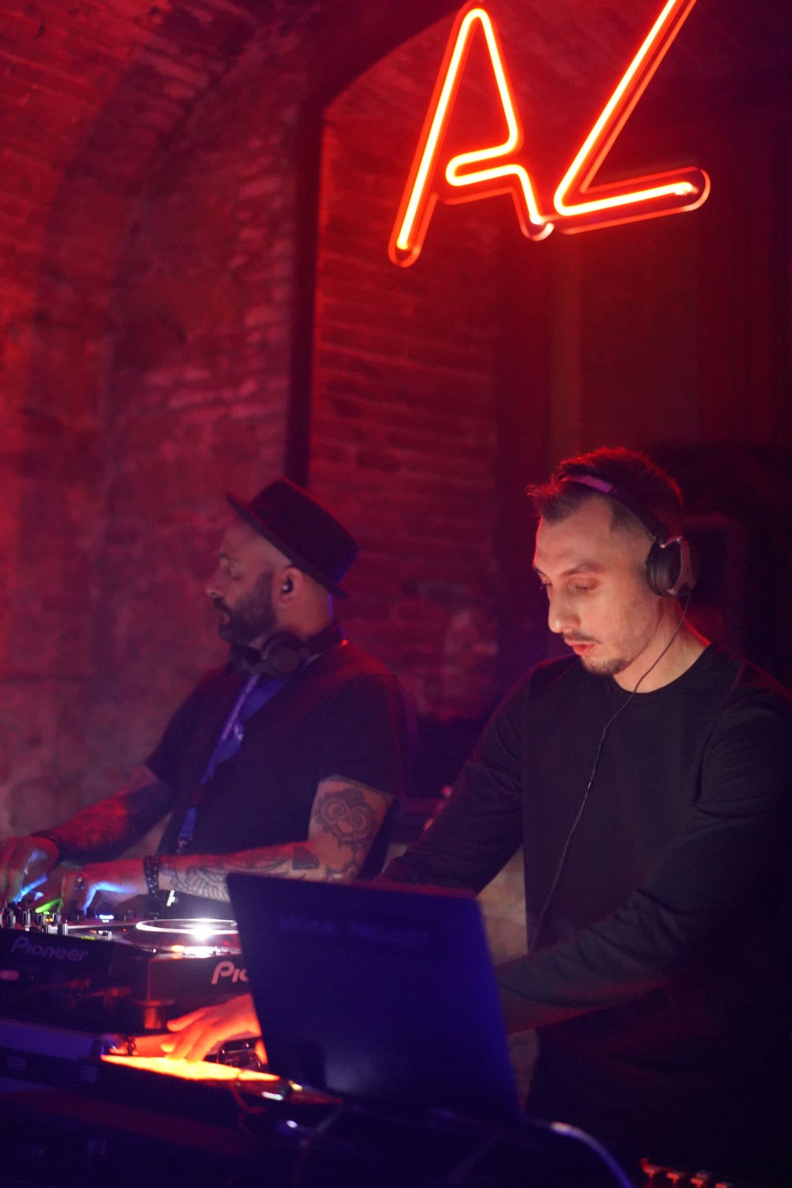 A DJ at the decks under dim red light