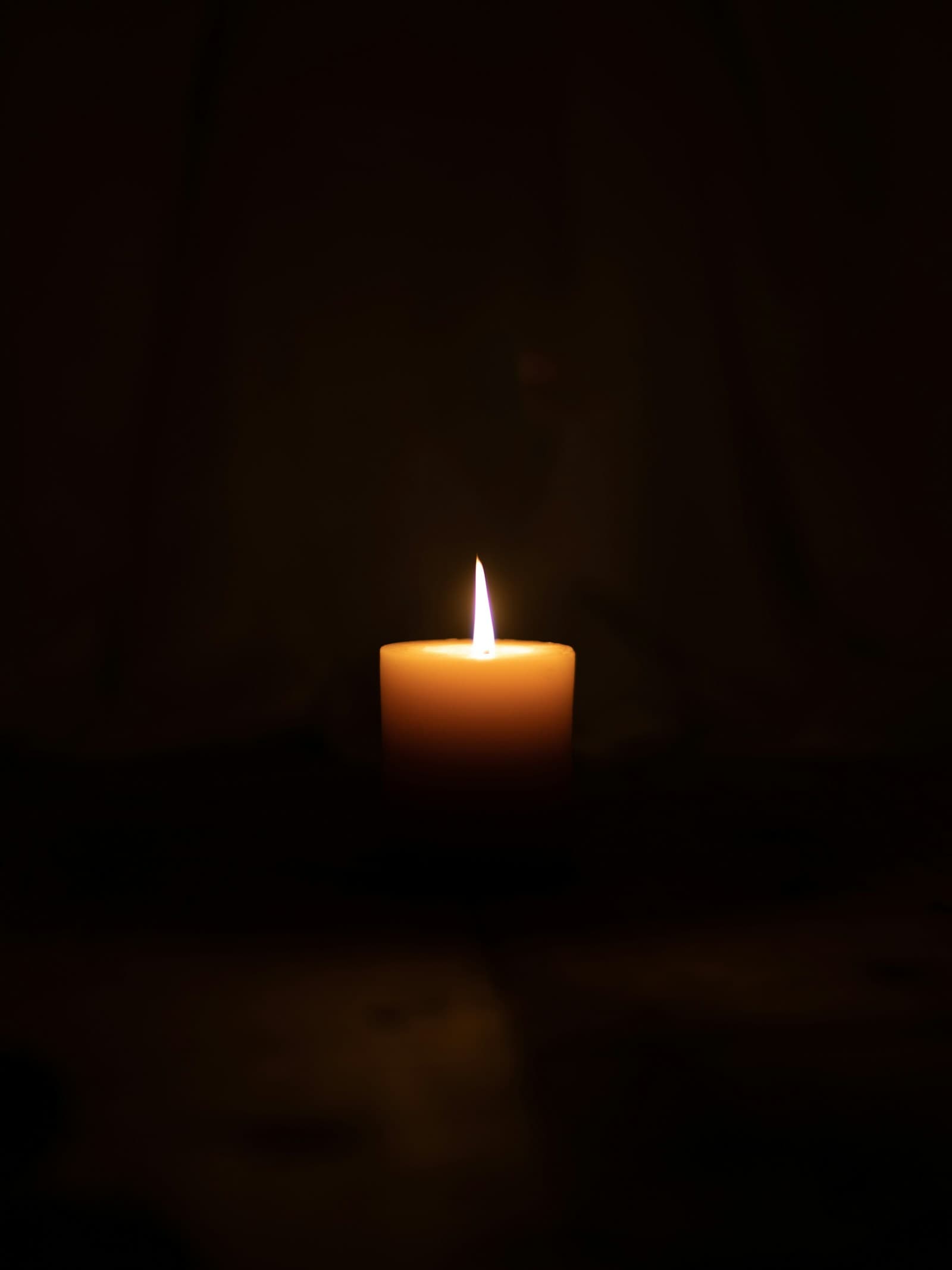 A single lit candle in deep darkness