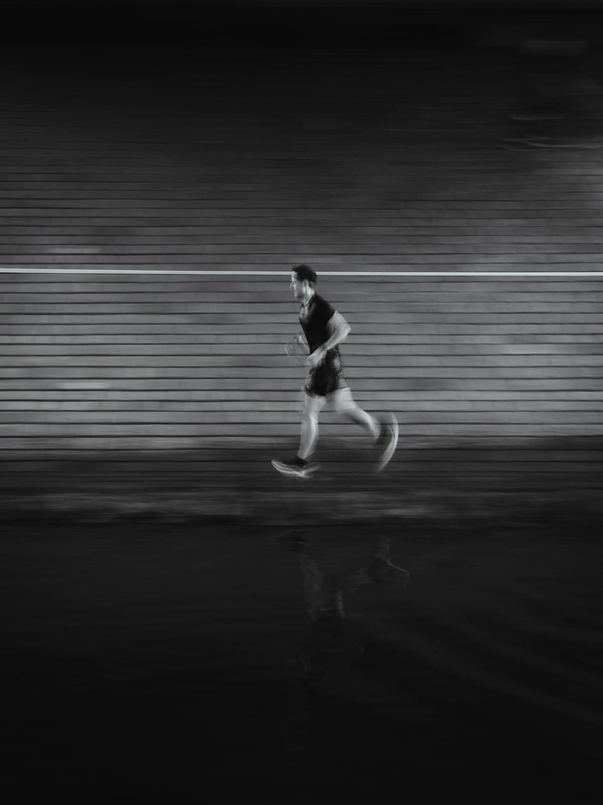 A lone runner blurred in motion against a dark wall