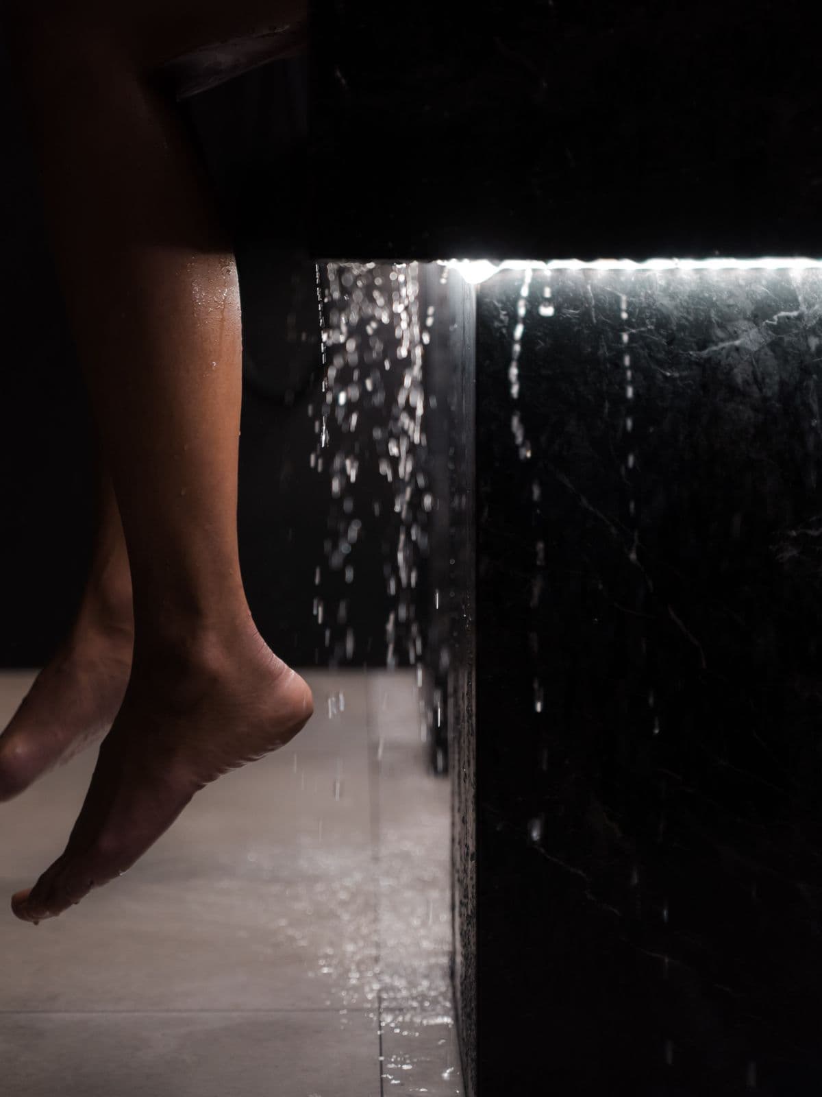Water falling against a backlit black-marble wall