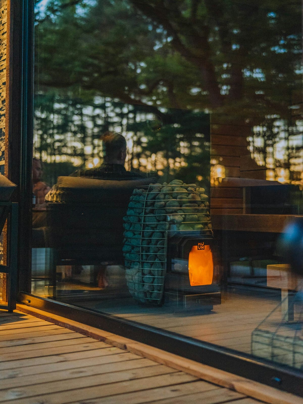 A warm wooden sauna at dusk, heater glowing in the dim