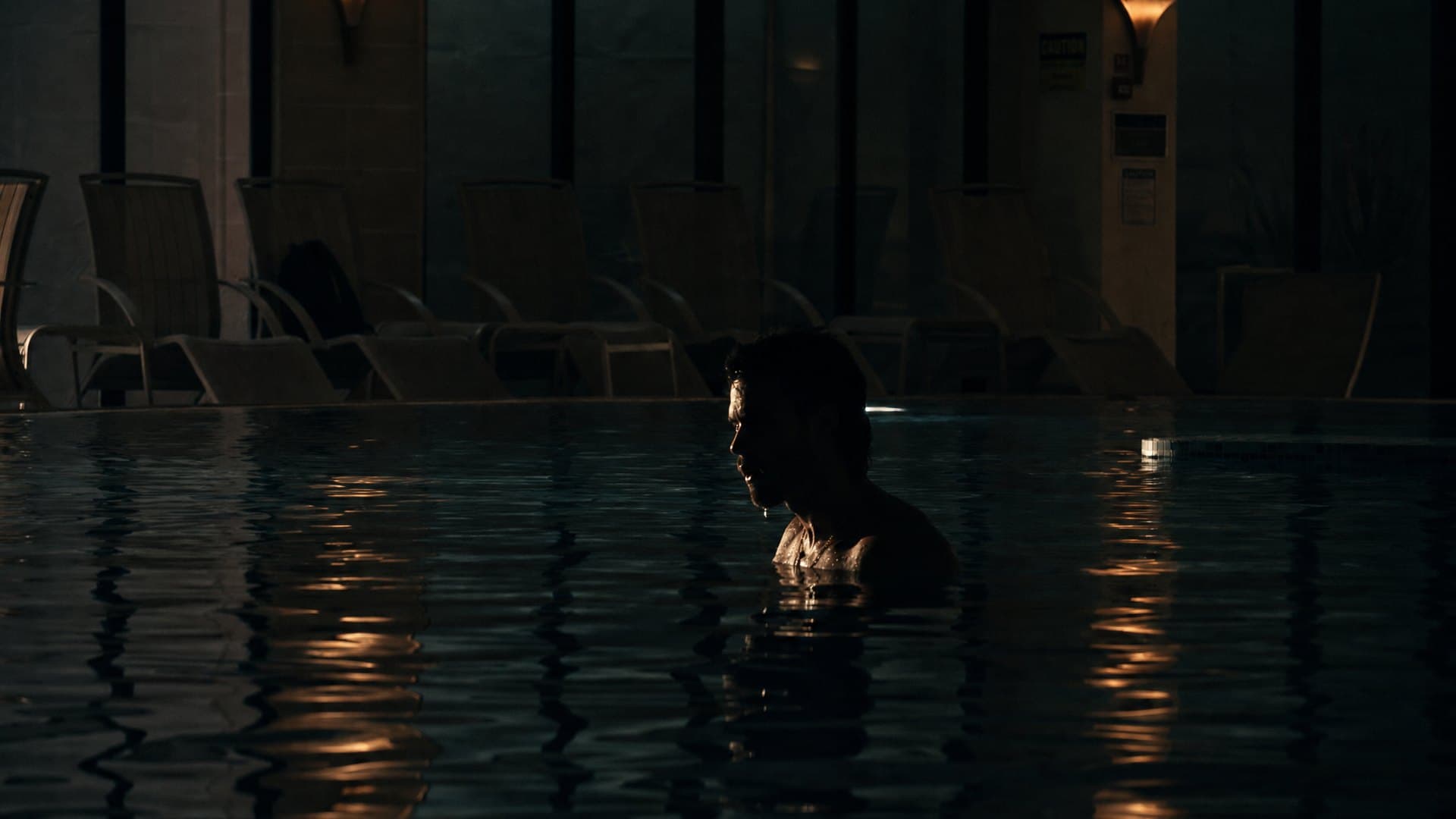 The indoor pool at night, loungers along the far edge