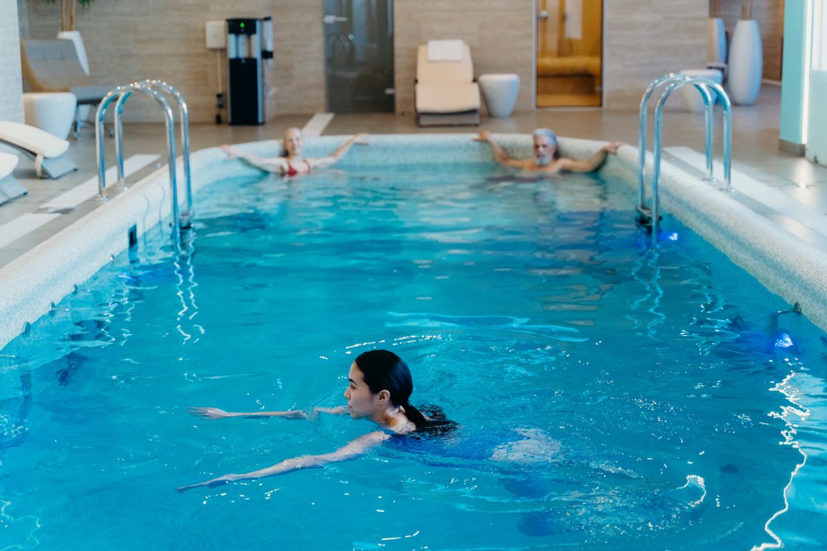 Adults relaxing in a serene indoor pool at a wellness club — gym vs wellness club Malta pool access