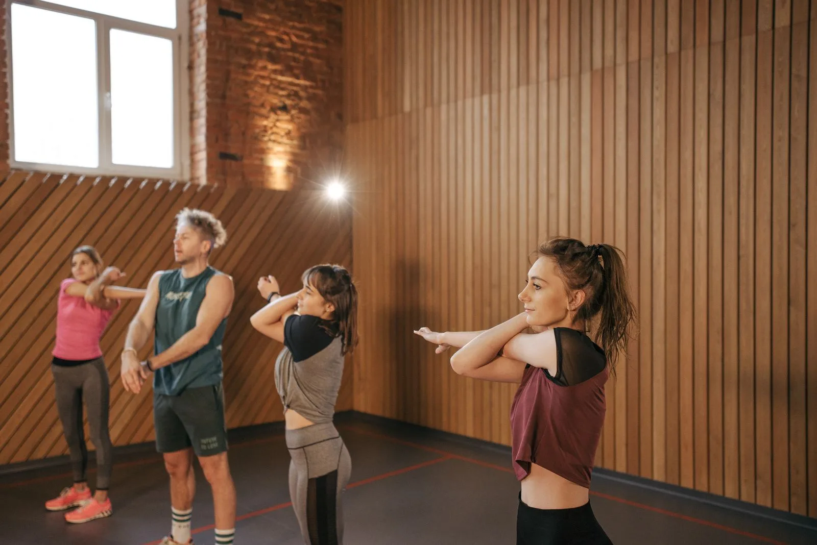 A group of adults stretching together during a session in a bright, welcoming space