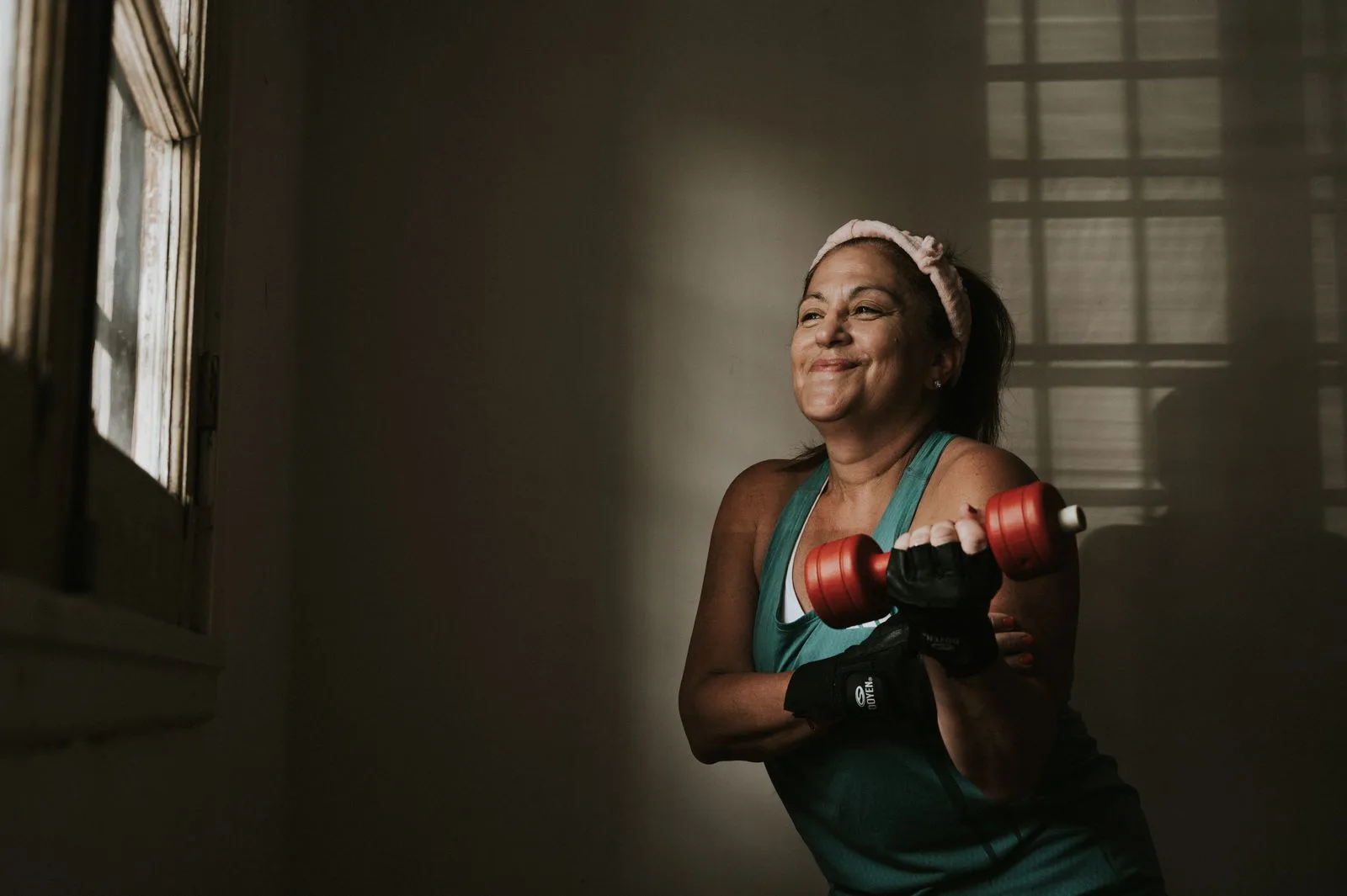 A woman lifting dumbbells indoors as part of strength training for longevity