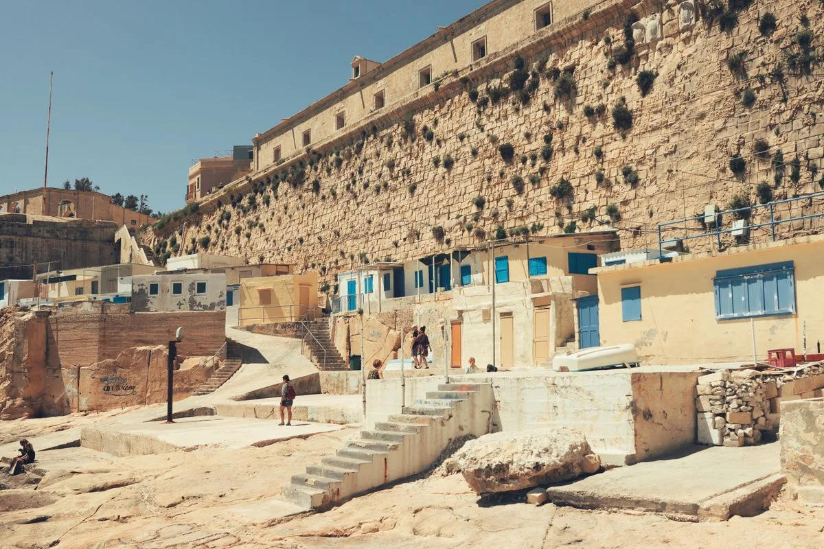 Sunlit stone walls of Valletta Malta in summer heat illustrating why indoor air conditioned gyms matter